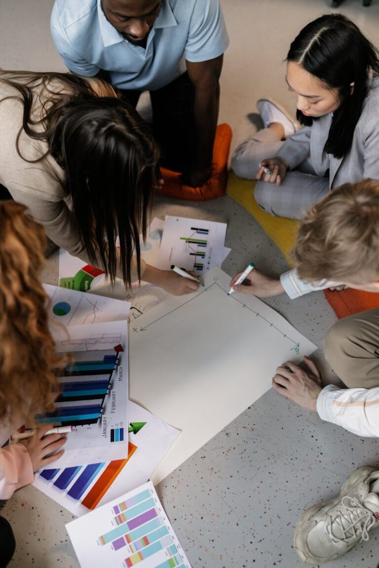 Group of diverse adults brainstorming project ideas on the floor with charts.